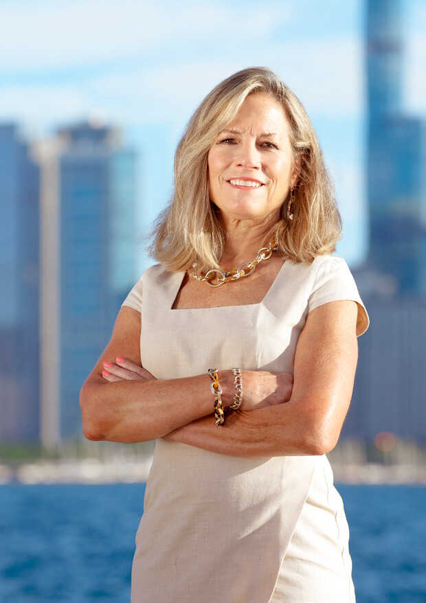 terri standing in front of city skyline and lake with arms crossed smiling